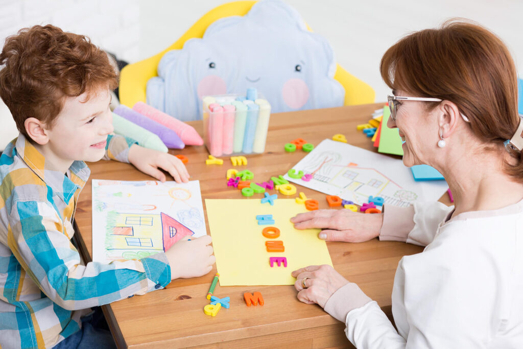 Child and adult working together at table with educational materials during learning activity. Learn the difference between developmental stages and ADHD with expert ADHD testing for kids in Fort Collins, CO.