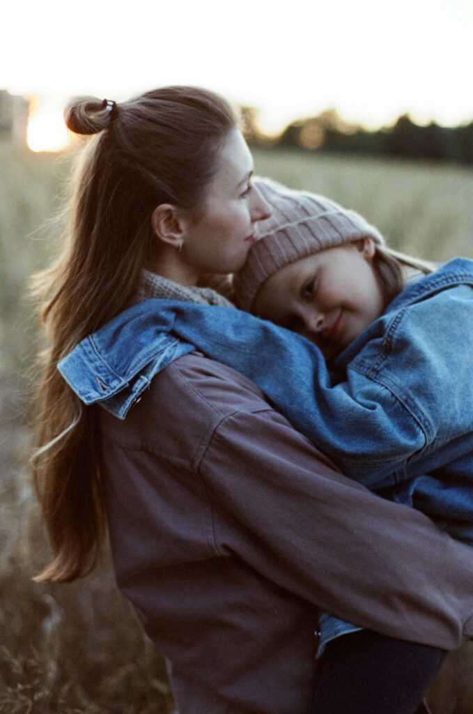 Mother holding young child close outdoors at sunset showing comfort and connection in natural setting. Stop wondering and get the support your family needs with compassionate ADHD testing for kids in Fort Collins, CO.