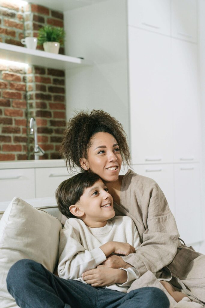 Happy mother and young son smiling and looking up together while sitting on couch in bright kitchen. Find targeted strategies to support your child's executive functioning skills with ADHD testing for kids in Fort Collins, CO.
